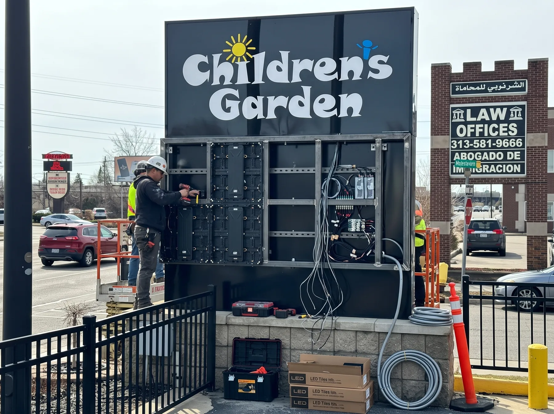 Technician working on the rear cabinet of Children's Garden outdoor LED monument sign in Dearborn